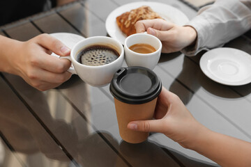 Friends drinking coffee at wooden table in outdoor cafe, closeup