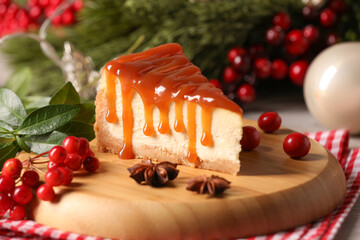 Tasty caramel cheesecake and Christmas decorations on table, closeup