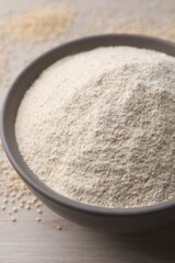 Ceramic bowl with quinoa flour and seeds on wooden table