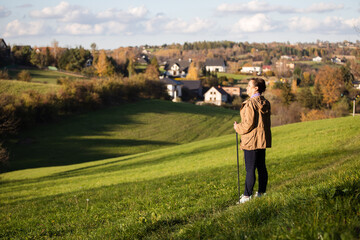 Nordic walking lady stands on a hill and watched the countryside view