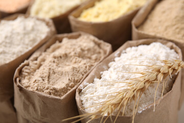 Paper sacks with different types of flour as background, closeup