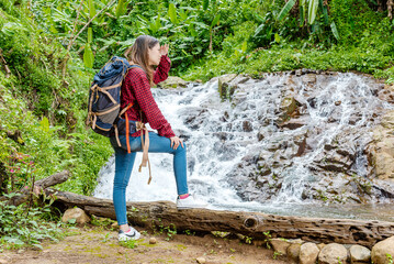 Asian woman in a hat and backpack looking around