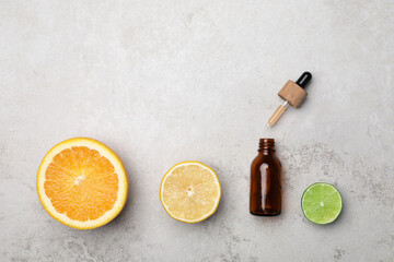 Bottle of citrus essential oil and fresh fruits on light table, flat lay. Space for text