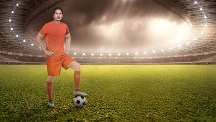 Asian football player man in a orange jersey standing with the ball