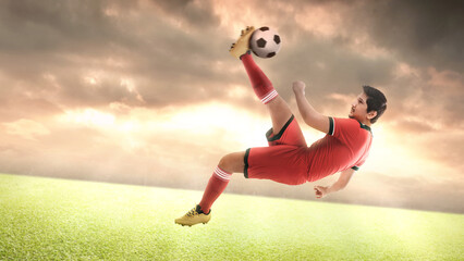 Asian football player man in a red jersey kicking the ball