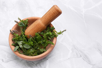 Mortar with pestle and mint leaves on light grey marble table, space for text