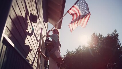 Cinematic Shot of a Father Holding His Small Daughter of His Shoulders, Helping Her to Raise the United States of America Flag to Celebrate a National Fourth of July Holiday at Their House.