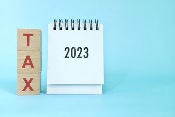 New year 2023 tax business and accounting concept. 2023 desk calendar with wooden blocks with word...