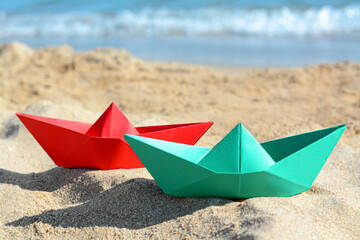 Fototapeta na wymiar Two paper boats near sea on sunny day, closeup
