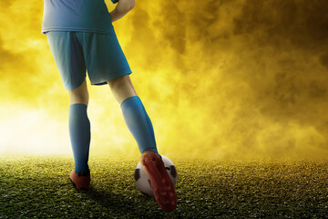Rear view of a football player man in a blue jersey kicking the ball