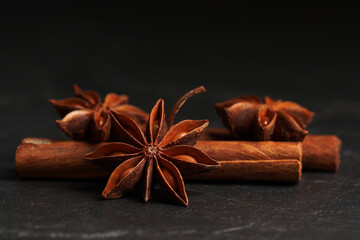 Aromatic anise stars and cinnamon sticks on black table