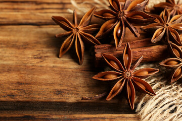 Aromatic anise stars and cinnamon sticks on wooden table, closeup