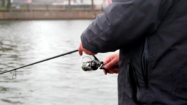 An angler spinning in a city canal in rainy weather.