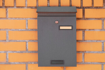 Black metal letter box on red brick wall