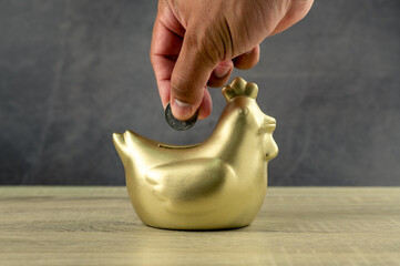 A man hand carrying to golden chicken bank 
,saving money concept	
