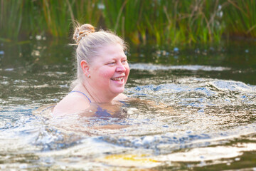 An elderly woman swims in the cool water of a garden pond. Hardening is her lifestyle. Adventure is ageless.