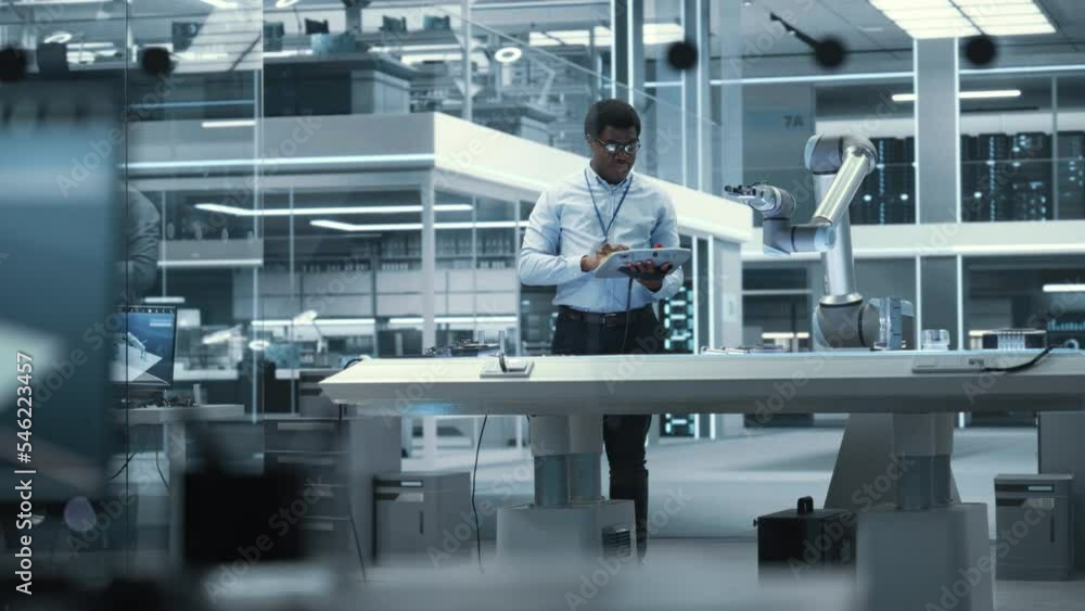 Aufkleber young african american male engineer using a tablet computer, researching and developing a futuristi