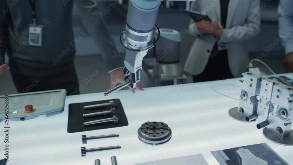 Aufkleber close up following footage of a modern robotic arm picking up and moving a mechanical metal componen