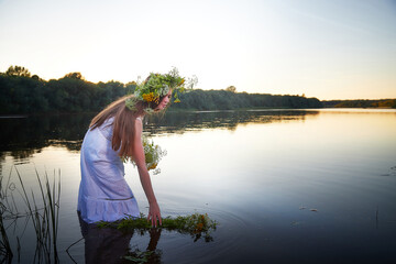 Portrait of beautiful slavic girl with long hair with flower crown in a water of river or lake on...