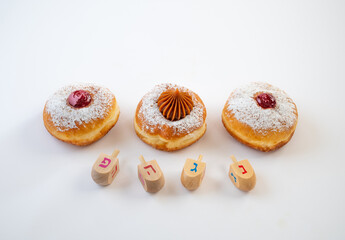 Fresh donuts with jelly and chocolate with  wooden dreidels  for Hanukkah celebration. Hebrew letters on wood dreidels say : Great Miracle Happened Hear.