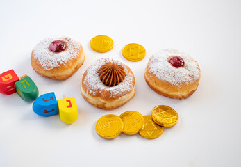 Fresh donuts with jelly and chocolate with  wooden dreidels  for Hanukkah celebration. Hebrew letters on wood dreidels say : Great Miracle Happened Hear.