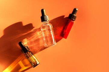Different glass dropper bottles with serum, oil, gel and beauty products on beige background....