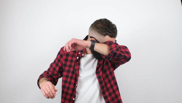 Young bearded hipster guy sweating a lot, smells bad. A man is worried and shows a problem with sweating, sniffing his armpit. Bad smell, excessive sweating concept.