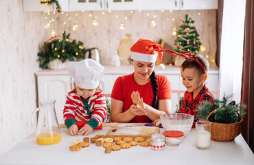 happy cheerful family mother and children bake Christmas cookies in the kitchen. decorated for Christmas. the concept of comfort and celebration