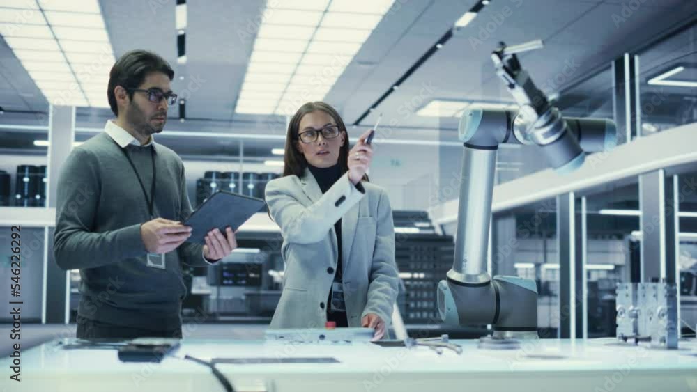Fototapete Robotics Engineer and Machinery Operator Collaborate on a Robot Arm Project at a Factory, Using a Tablet Computer to Operate the Robot Arm in Scientific Technology Lab.