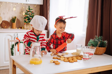 a happy family of cheerful kids cooks dough, bakes cookies in the kitchen. The concept of celebration and comfort