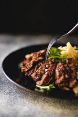 Appetizing meat salad with cheese and vegetables on a stylish dark plate. Restaurant supply. Waiter. Banquet