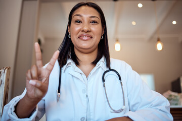 Doctor, black woman and peace sign in video call, hospital and smile with happiness, proud and...