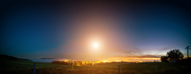 full moon low over the horizon in the early morning over the city