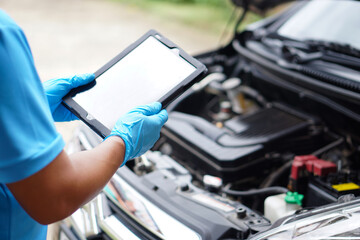 Mechanic is checking car engine, use smart tablet to record and diagnose the problems of engine        Concept : using technology to manage car engine. Car service and maintenance.      