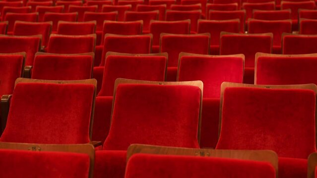  seats of the auditorium in the concert and theater hall. a ray of light runs through the theater seats. red upholstery of soft chairs and a beam of light from a theater lighting fixture
