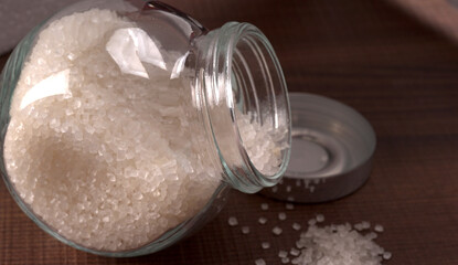Bowl and spoon with sugar on wooden background.