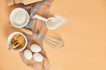 Bakery  or cooking frame, ingredients, kitchen items for pastry on pastel orange background. Top view, copy space.
