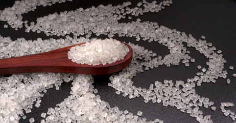 Bowl and spoon with sugar on wooden background.