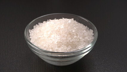 Bowl and spoon with sugar on wooden background.