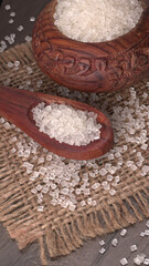 Bowl and spoon with sugar on wooden background.