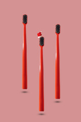 Three red toothbrush with red and white Santa hat floating on pink background with copy space. Dental medical Christmas and New Year concept. Creative medical health still life levitation.