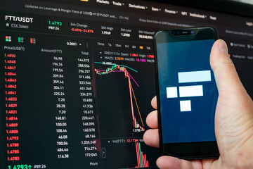 Man holding phone with FTX logo. Global fall of cryptocurrency graph - FTT token fell down on the...
