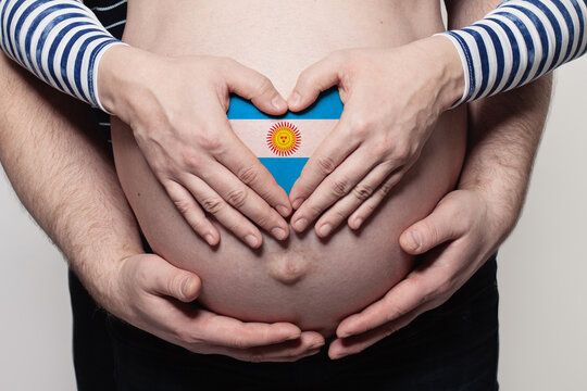 Argentine family concept. Man embracing pregnant woman belly and heart with flag of Argentina colors closeup
