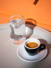 Espresso served with a glass of water on grey table