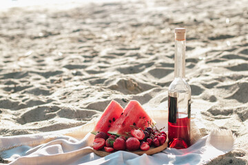 Champagne with a tray of fruits, strawberries and cherries on a picnic.