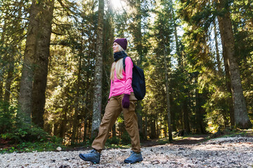 Fototapeta premium A young woman walks through the forest with a backpack. Active lifestyle