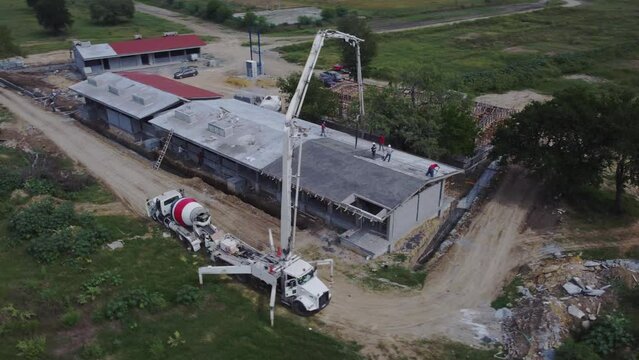 Aerial shot of concrete slab pouring construction with pump and mixer truck in open field
