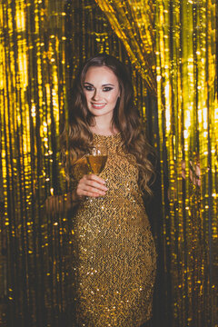 Beautiful woman celebrity with makeup wearing gold dress on golden bokeh background
