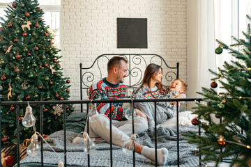 Happy family near fir-tree in bedroom, Christmas celebration at home