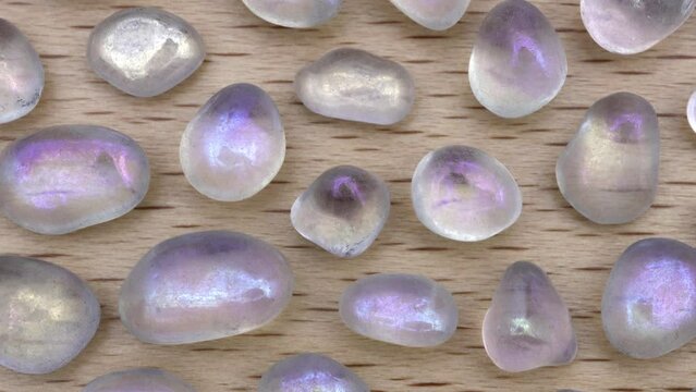 Shimmerstone rare jewel stones texture on light varnished wood background. Moving right seamless loop backdrop.